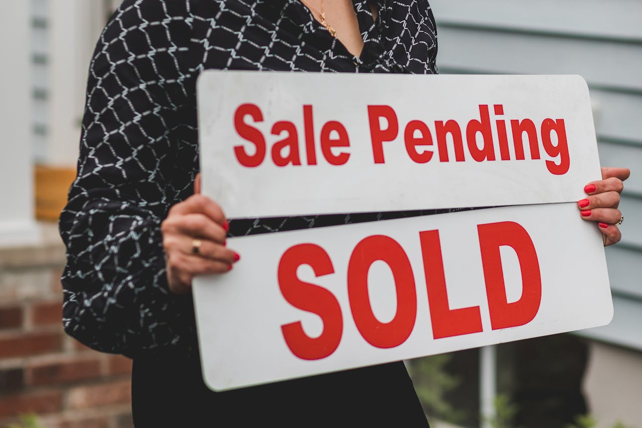A businesswoman holding Sale Pending and Sold signs indicating a successful real estate transaction.